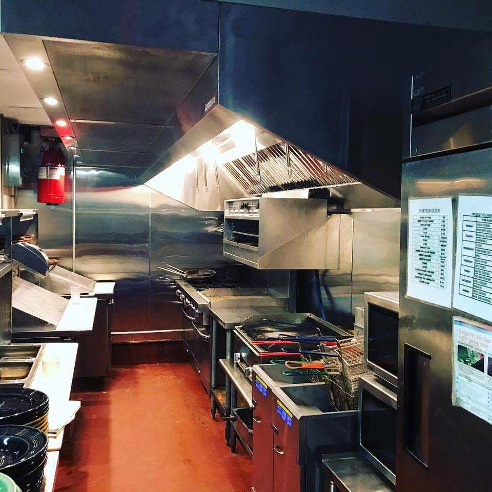 A kitchen with a lot of stainless steel appliances and a fire extinguisher