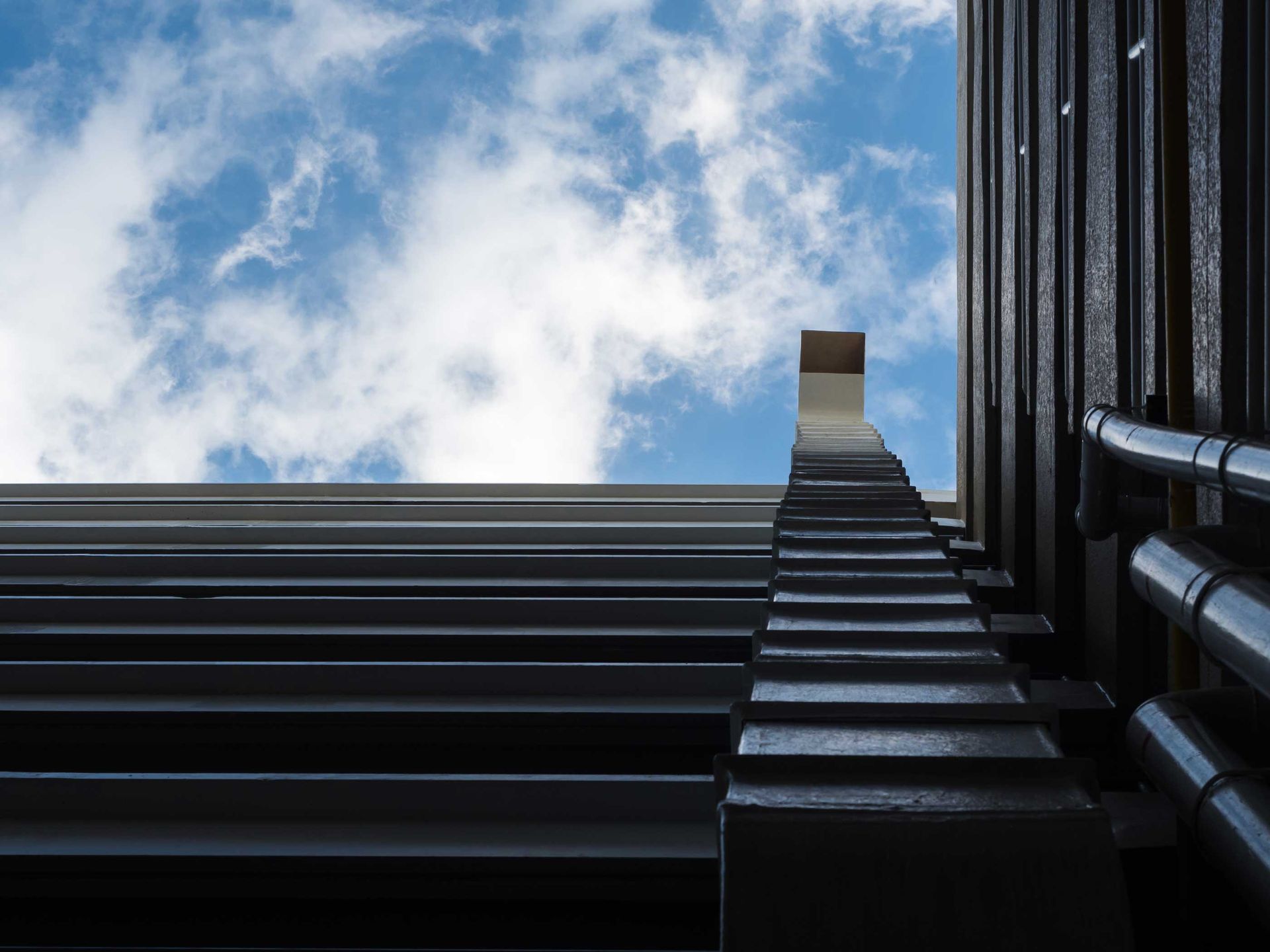 A staircase leading up to a blue sky with clouds.