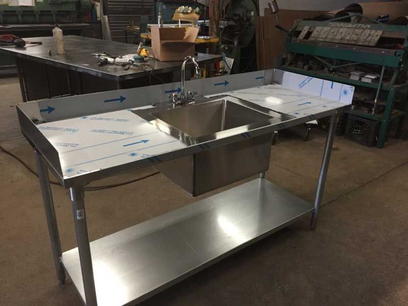 A stainless steel sink with a shelf underneath it