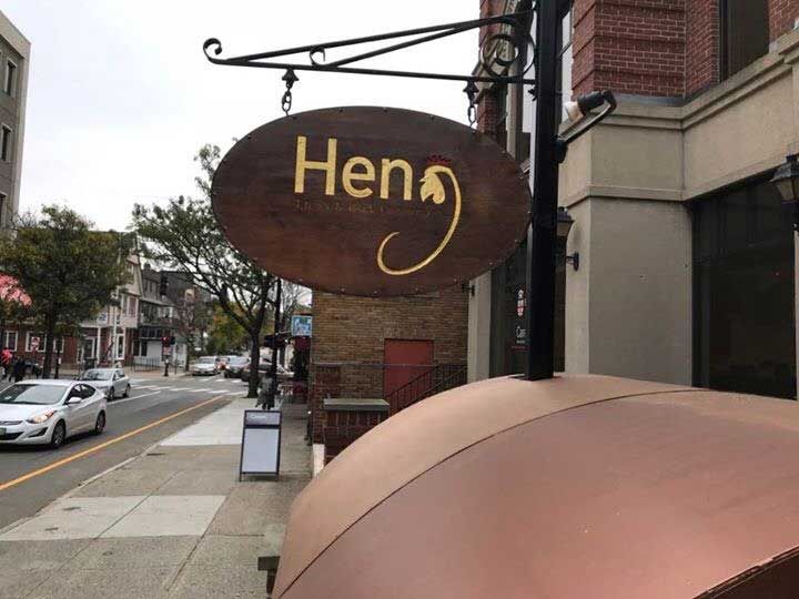 A sign that says hen on it is hanging from a pole