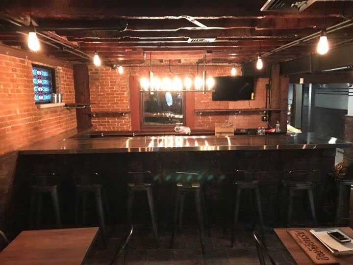 A kitchen with a brick wall and a stainless steel counter top