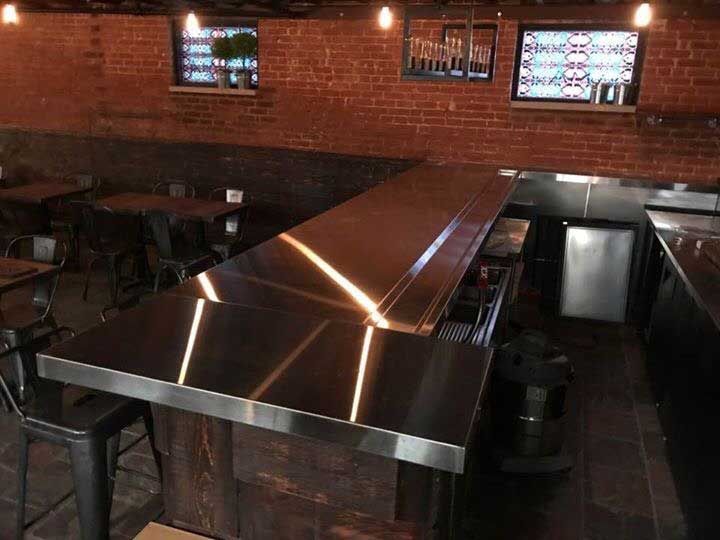A stainless steel bar in a restaurant with tables and chairs