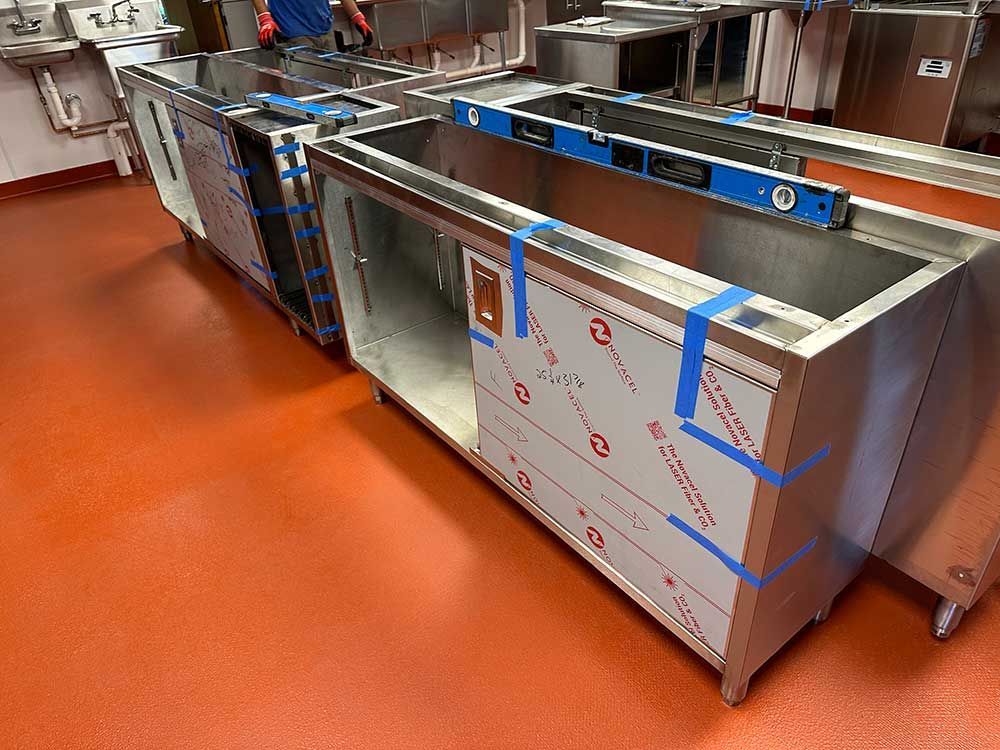 A row of stainless steel cabinets are being built in a kitchen.