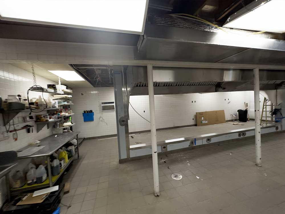 An empty kitchen with stainless steel appliances and shelves.