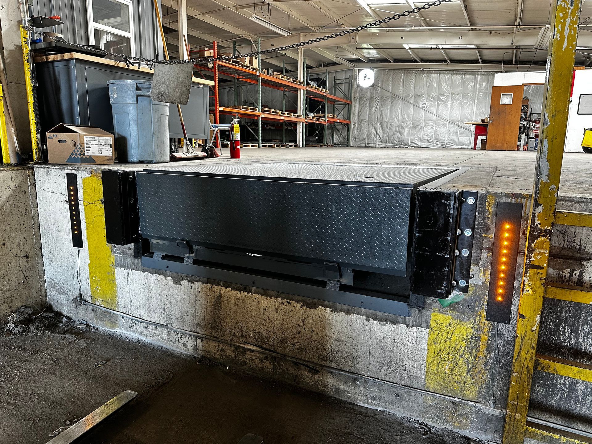 Industrial loading dock with a black metal barrier and yellow safety markings inside a warehouse