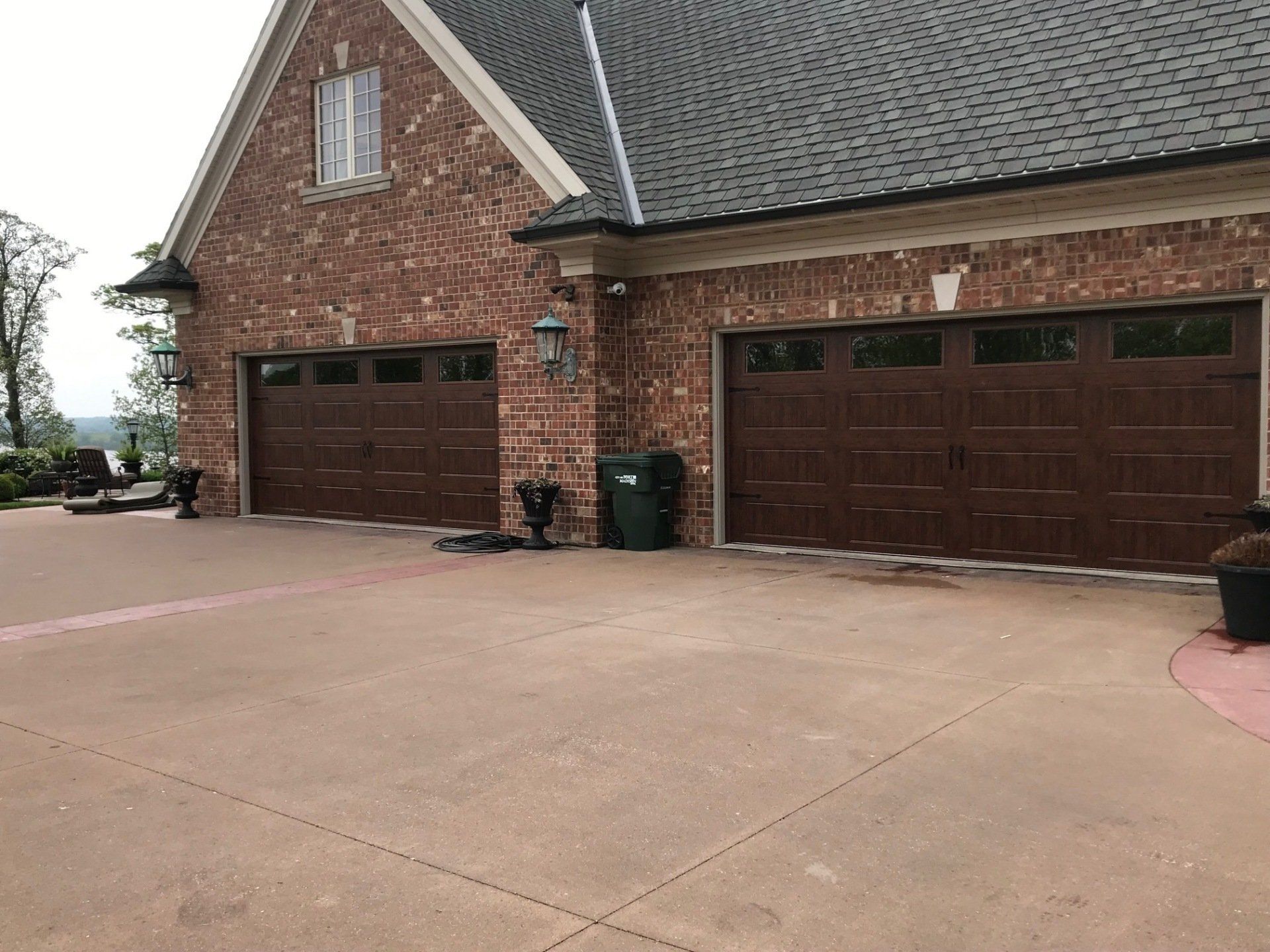 There are two garage doors on the side of a brick house.
