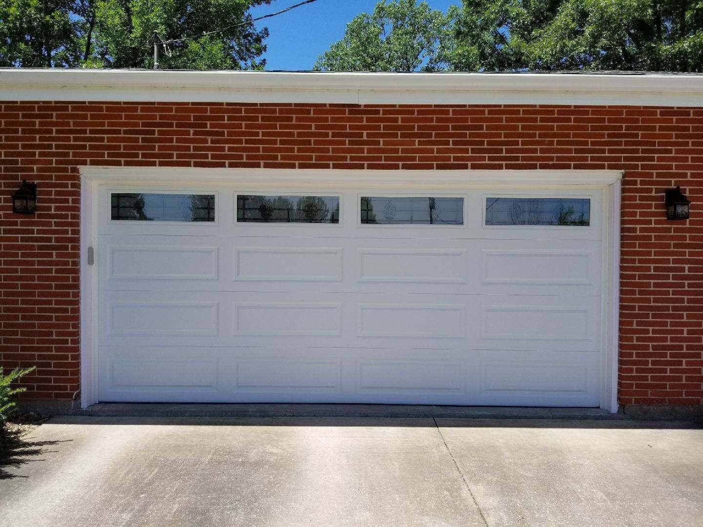 A white garage door is on a brick building