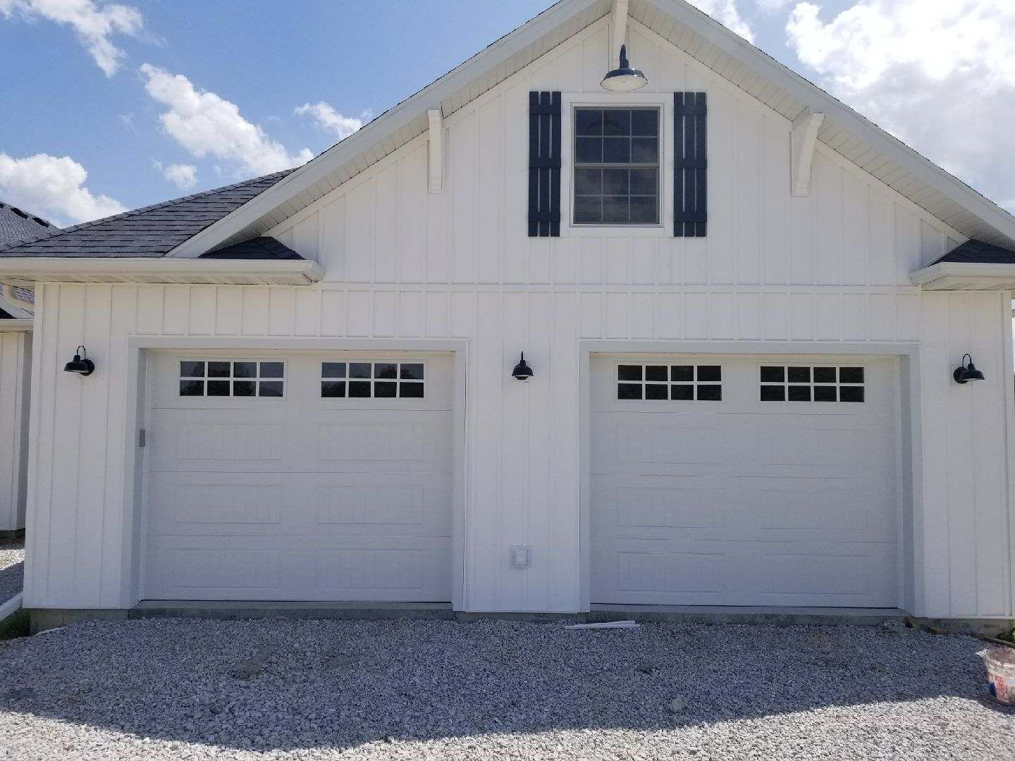 A white house with two garage doors and black shutters