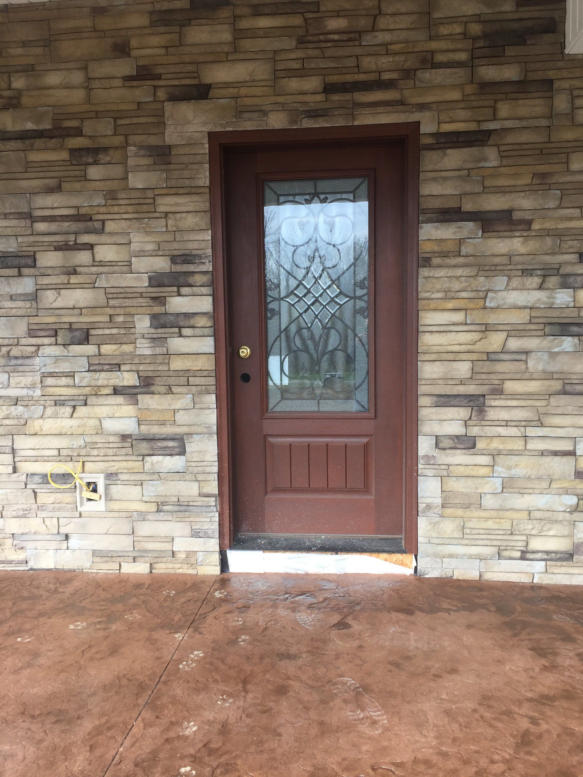 A brown door with a stained glass window on a stone wall