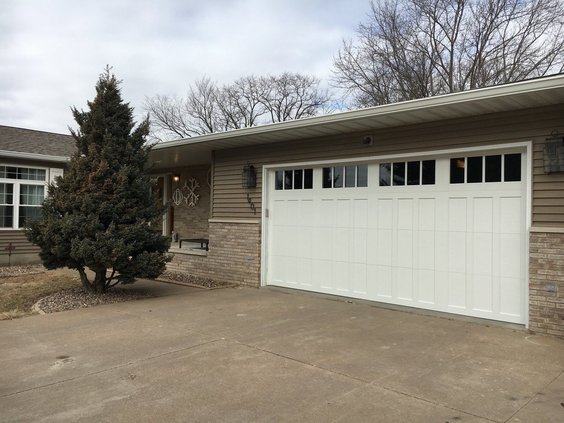 A white garage door is sitting in front of a house.
