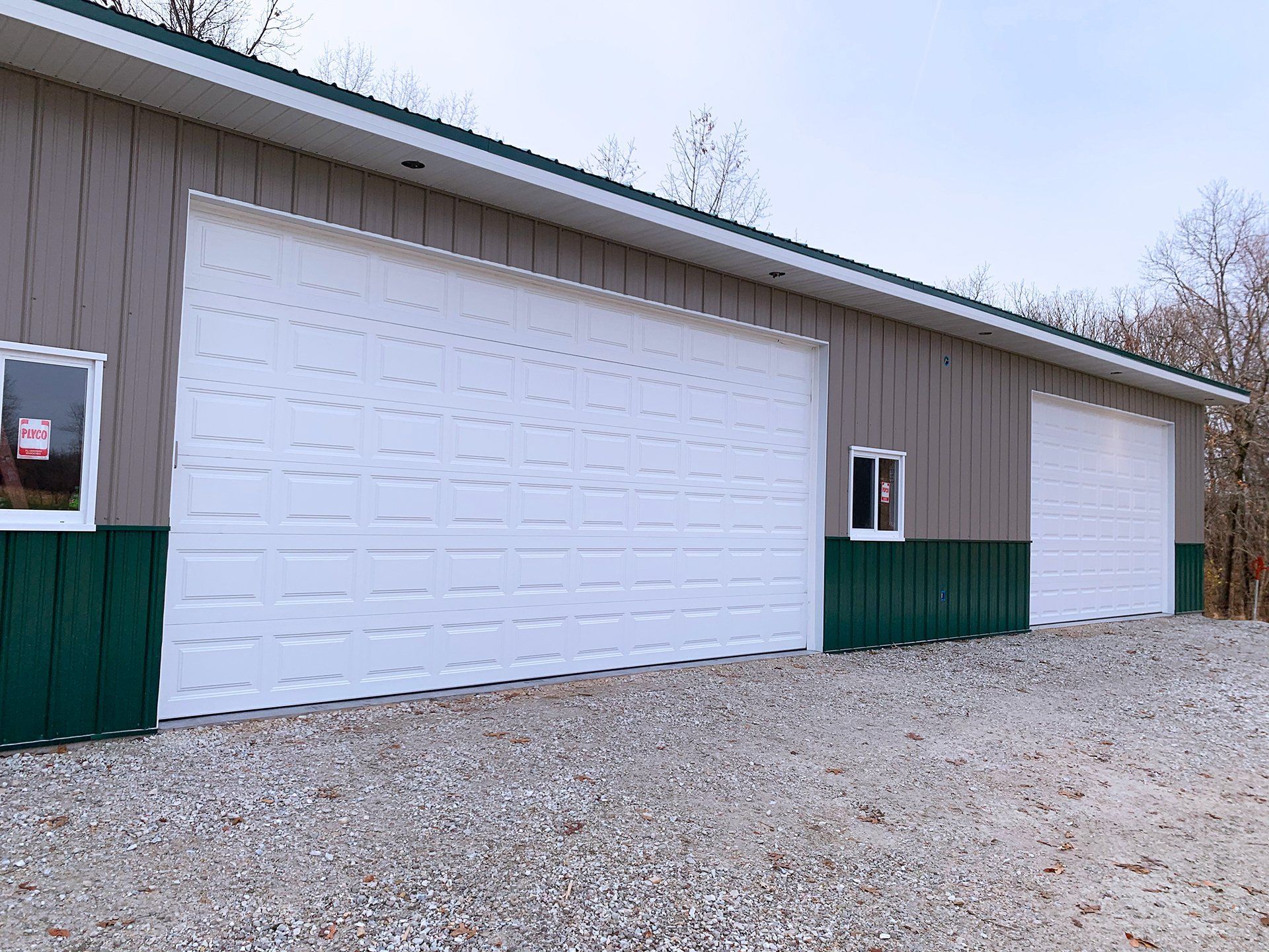 A large garage with two white garage doors and two windows.