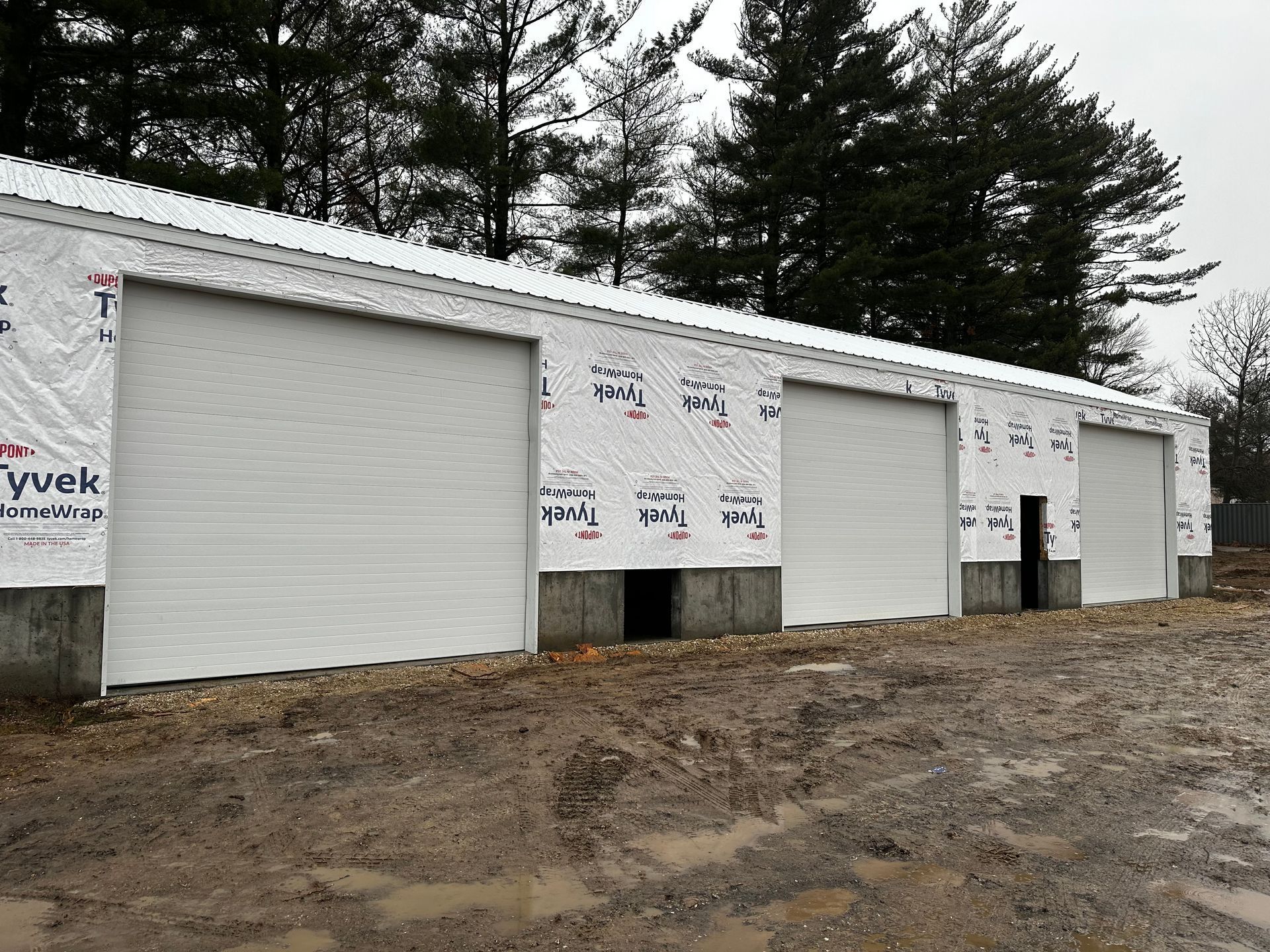 A row of white garage doors with trees in the background