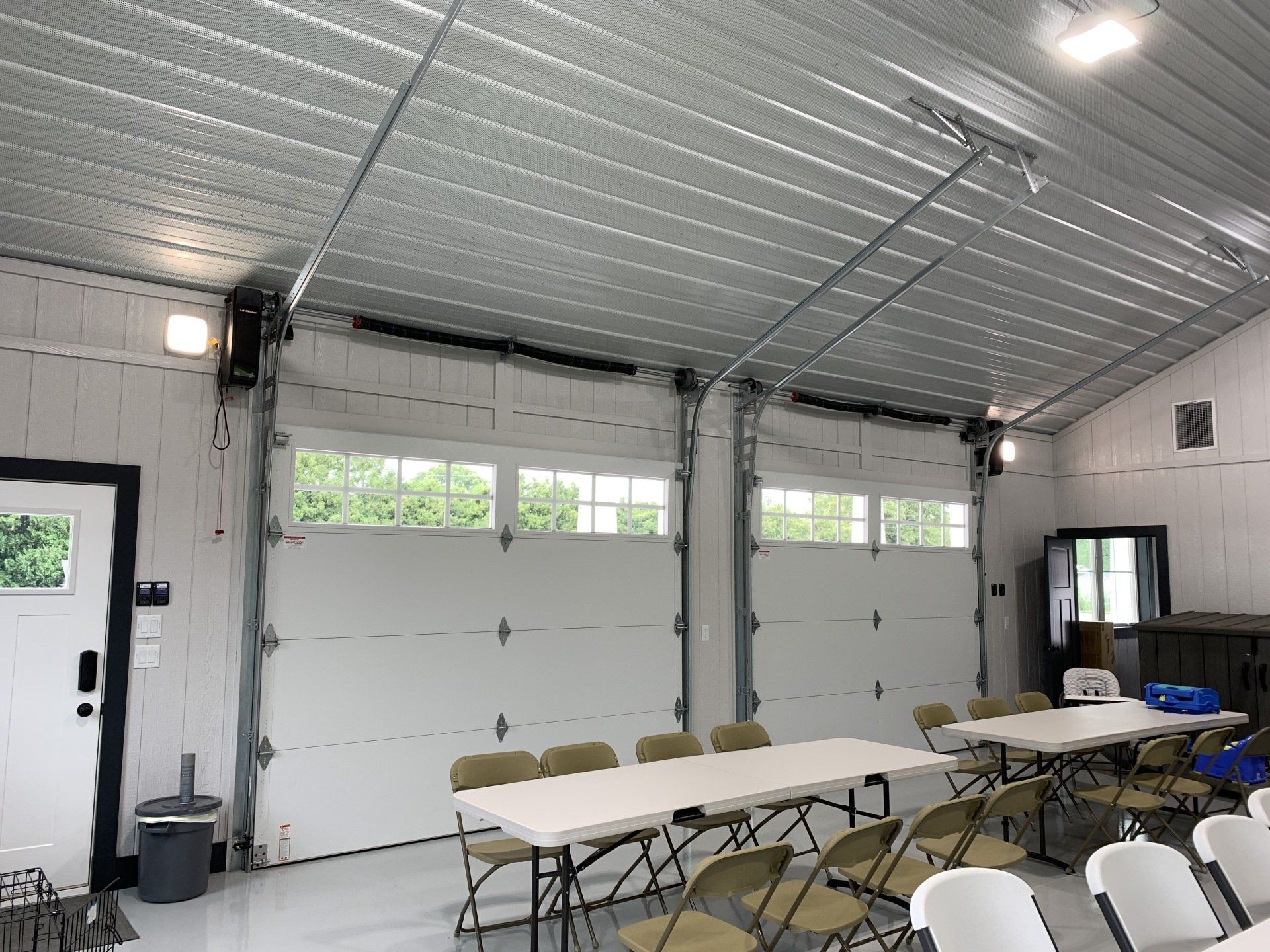 A room with tables and chairs in front of a garage door.