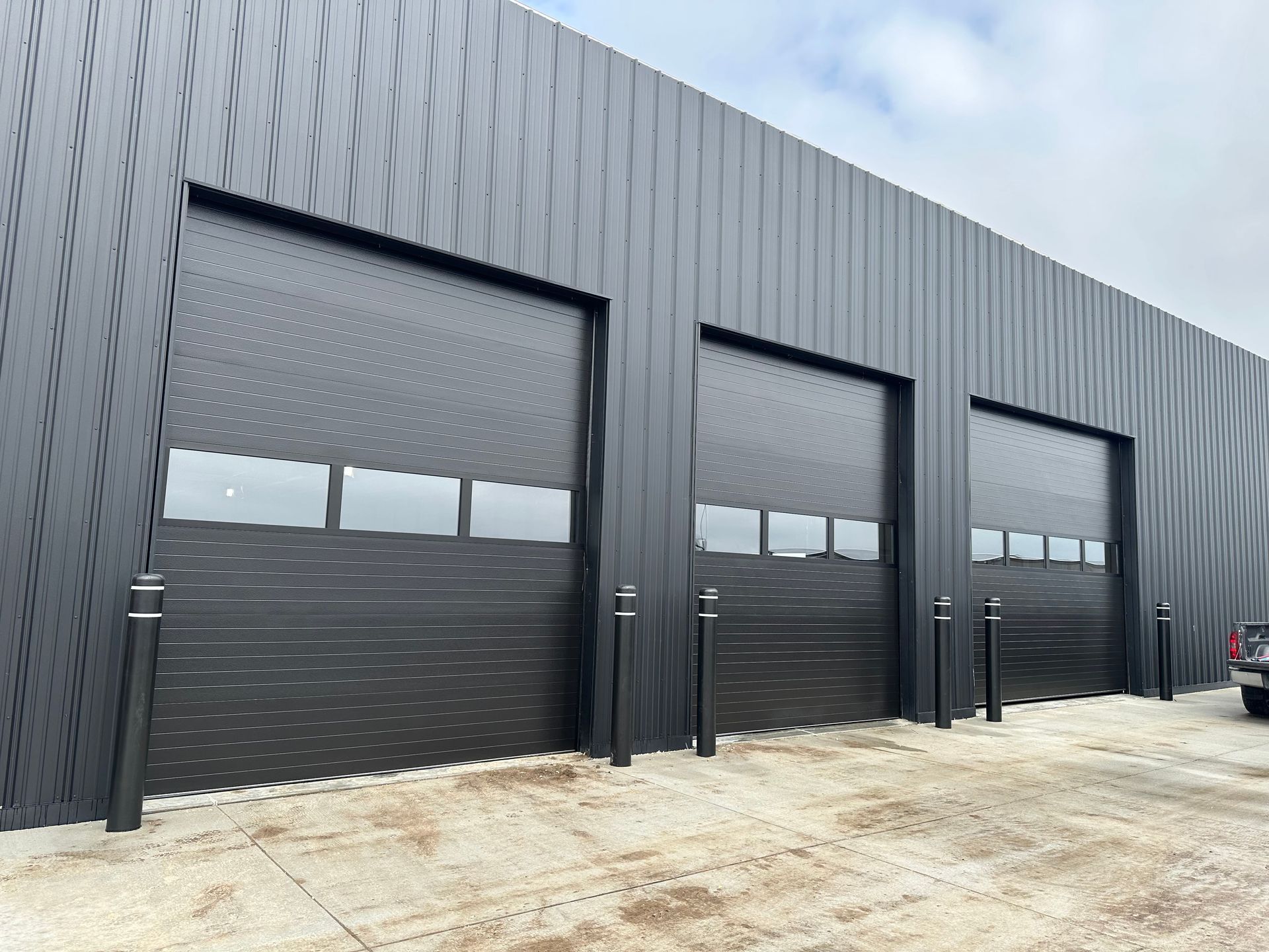 A row of black garage doors on the side of a building.