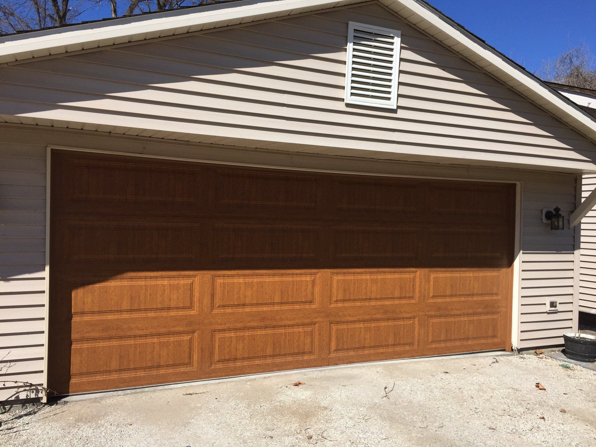 A large brown garage door is sitting in front of a house.