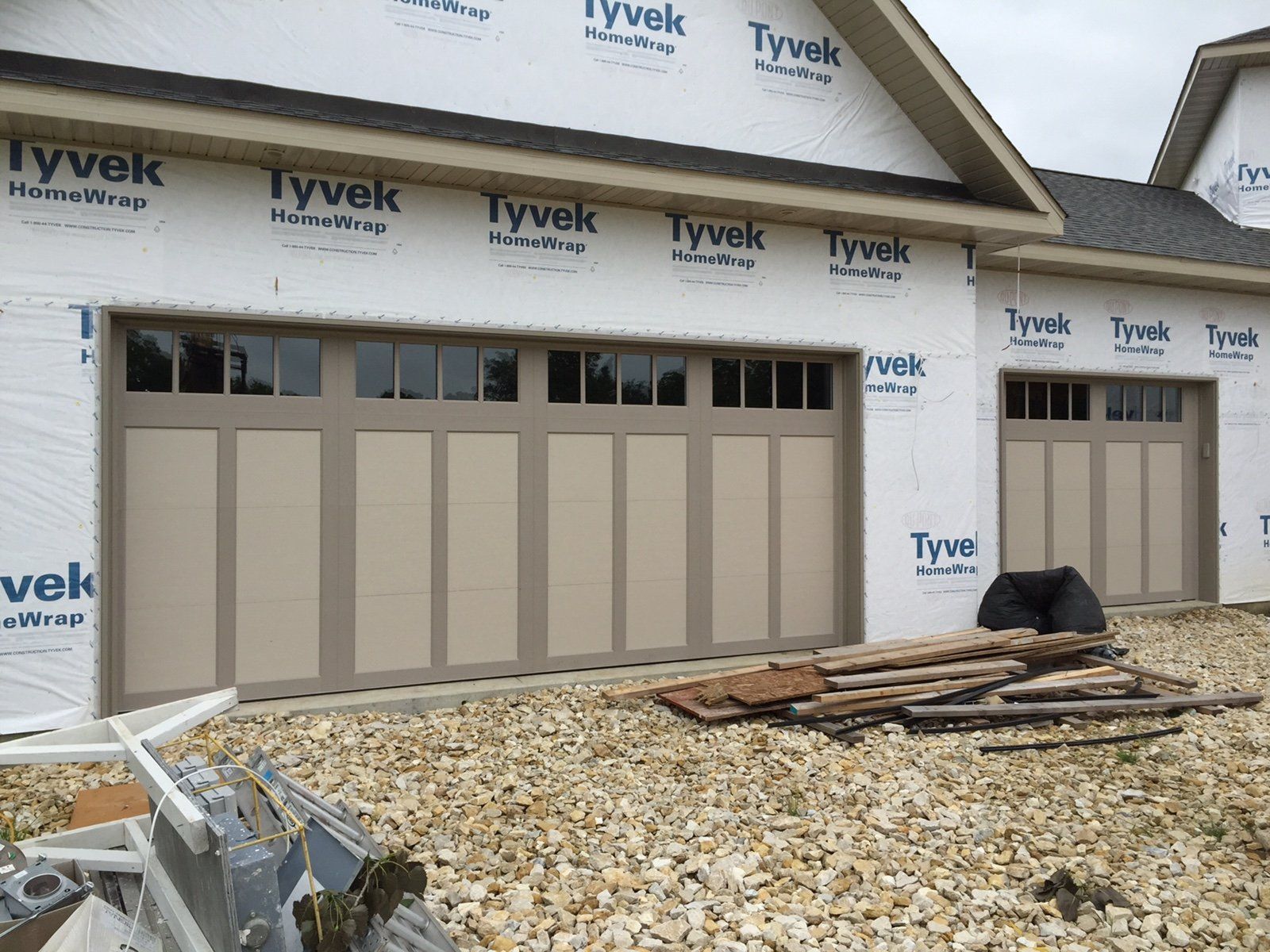 A garage door is being installed on a house under construction.