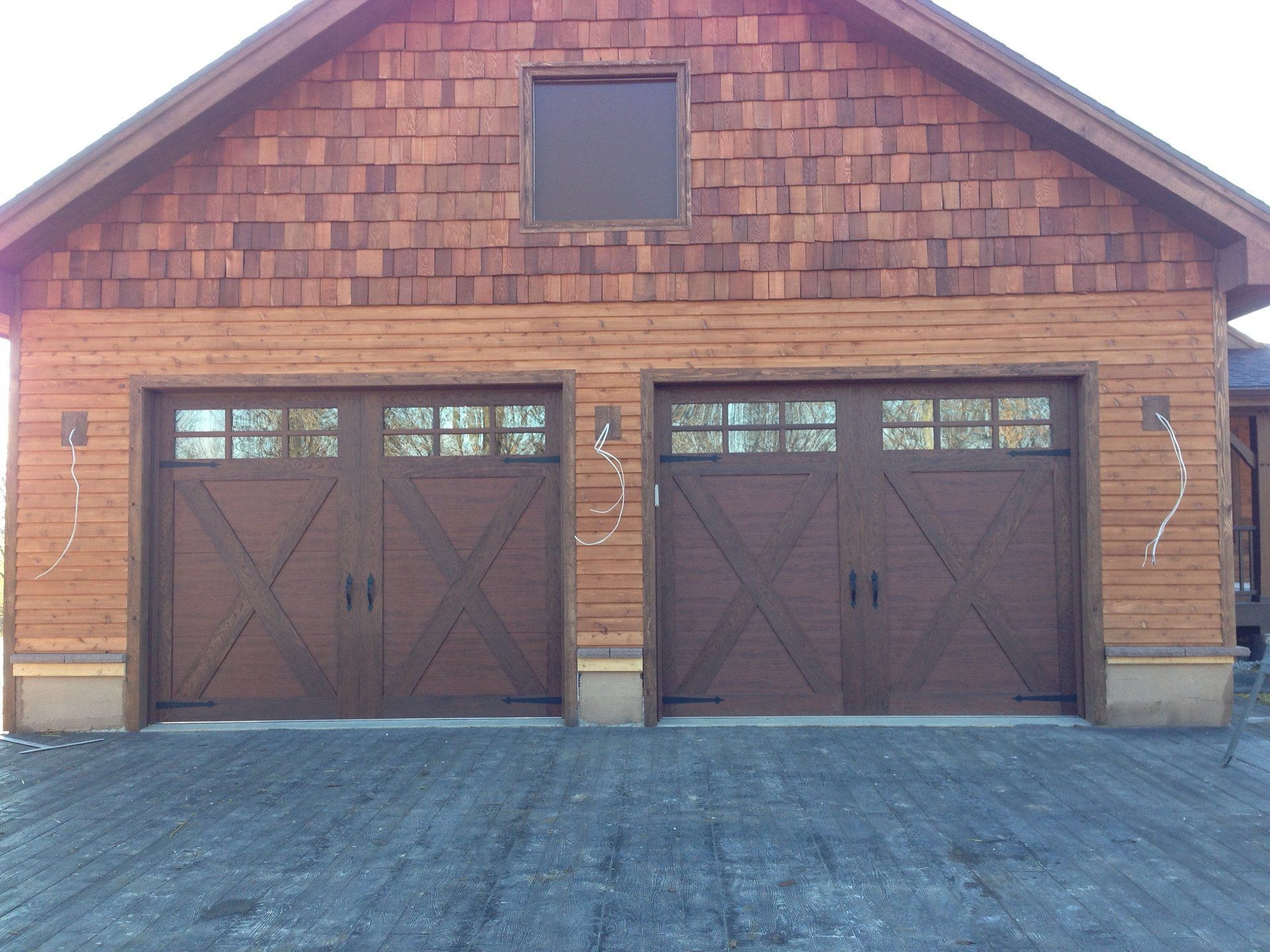 A wooden garage with three doors and a window