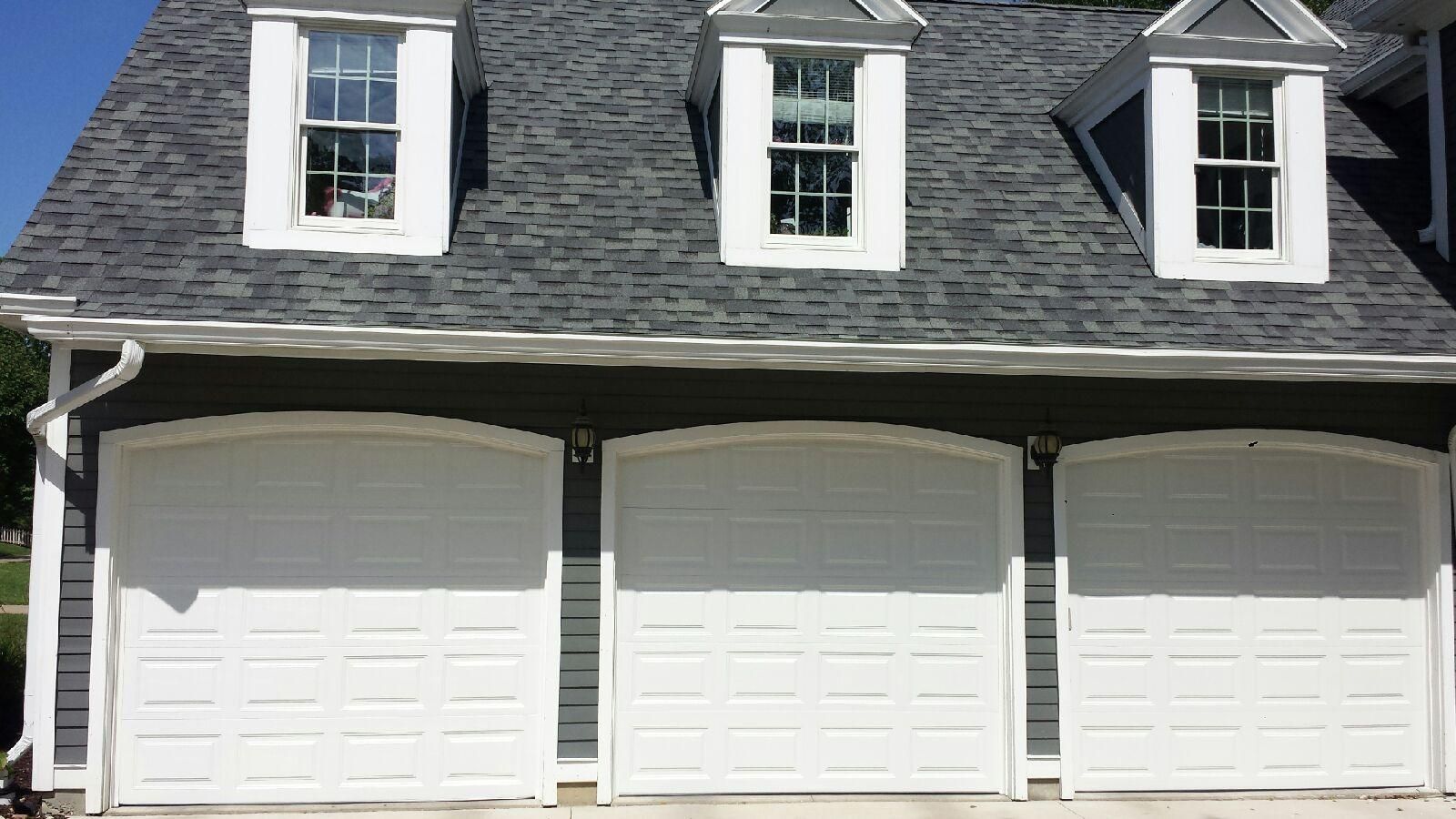 A large house with three white garage doors and a gray roof.