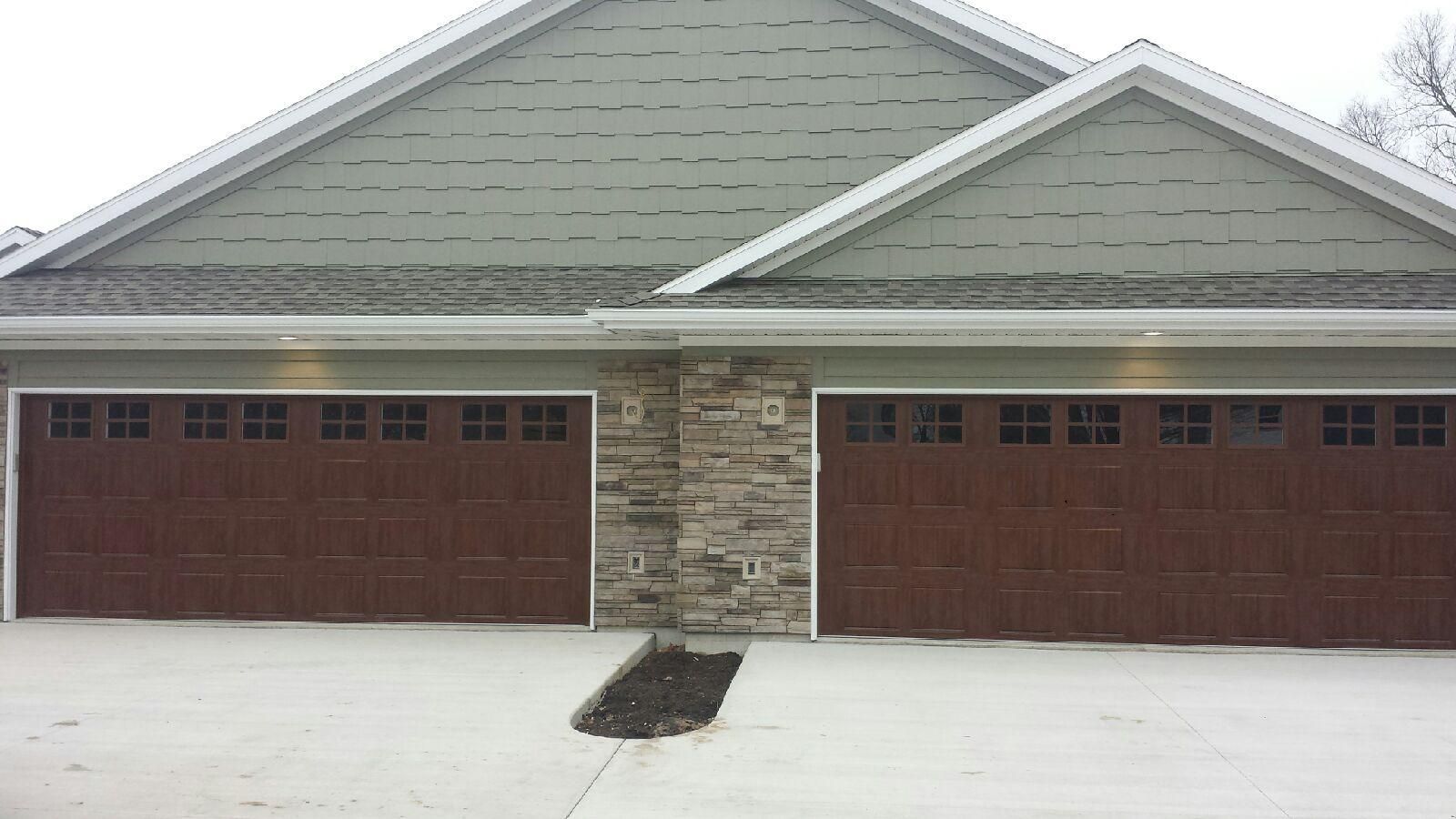 A house with two garage doors and a stone wall