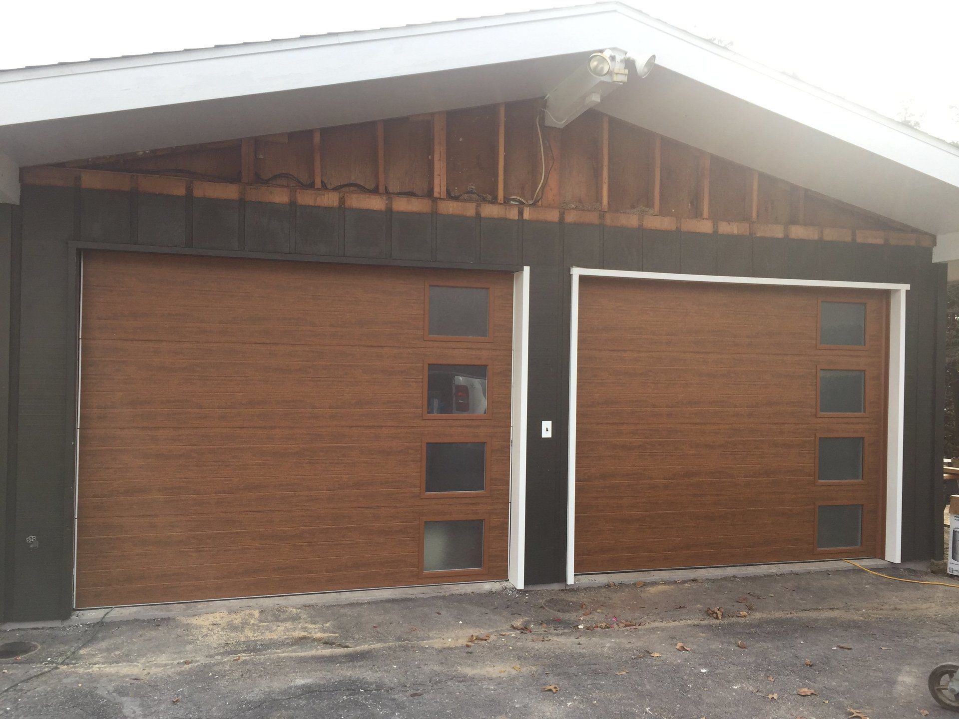 A house with two wooden garage doors and a black roof