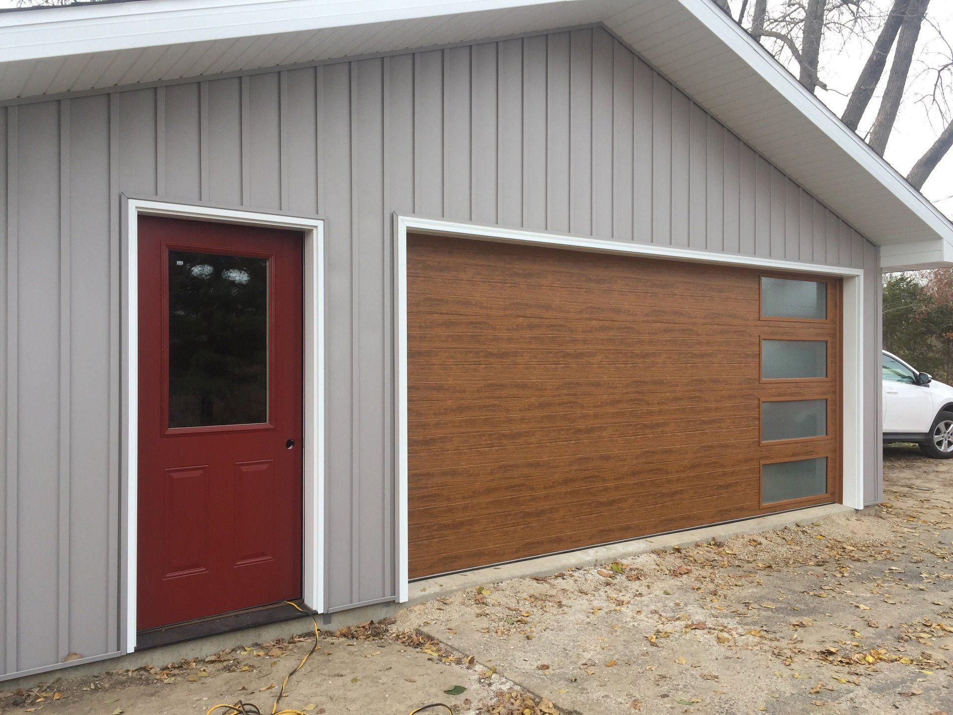 A garage with a red door and a white car parked in front of it.