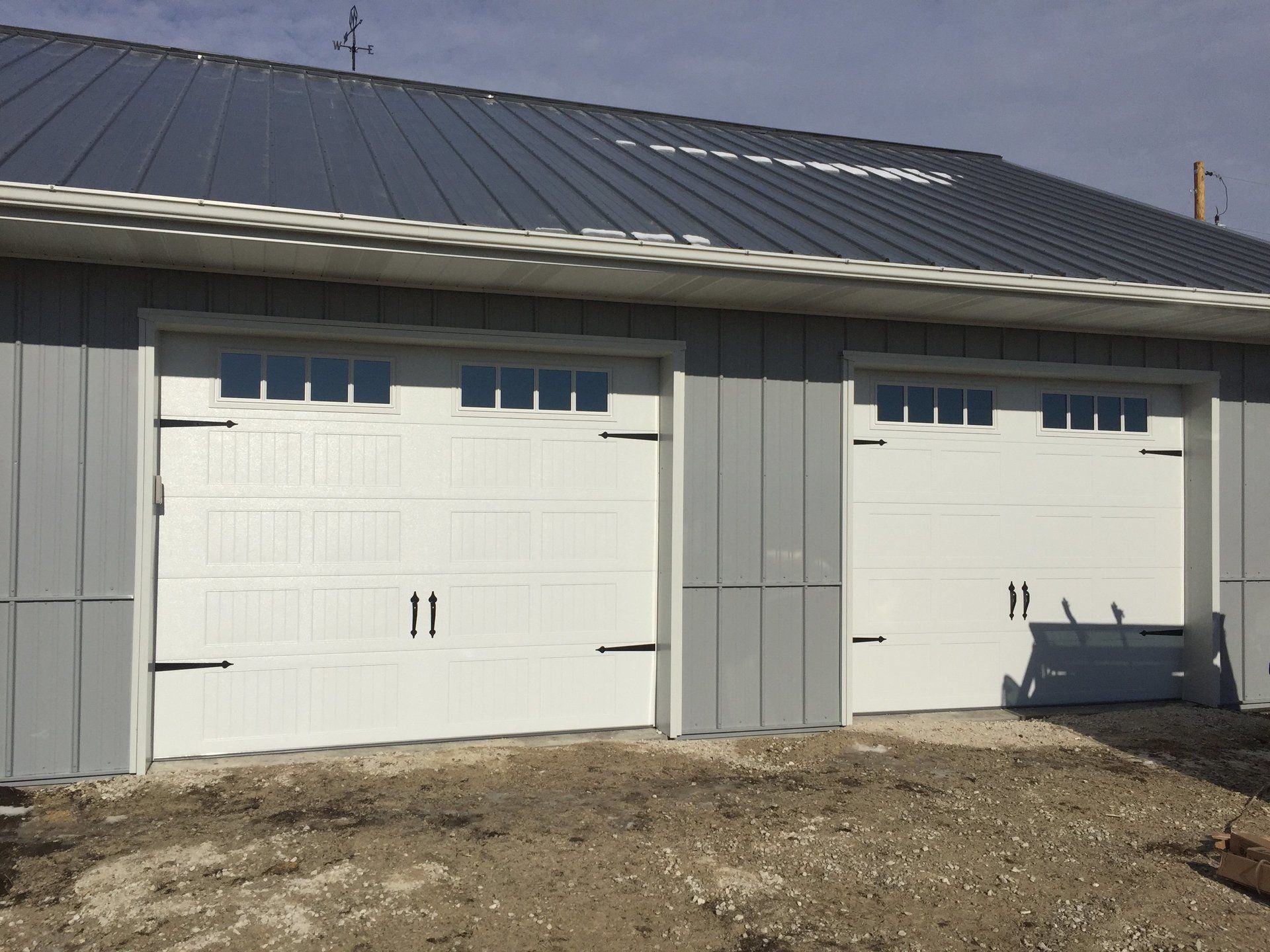 A garage with two white garage doors and a metal roof.