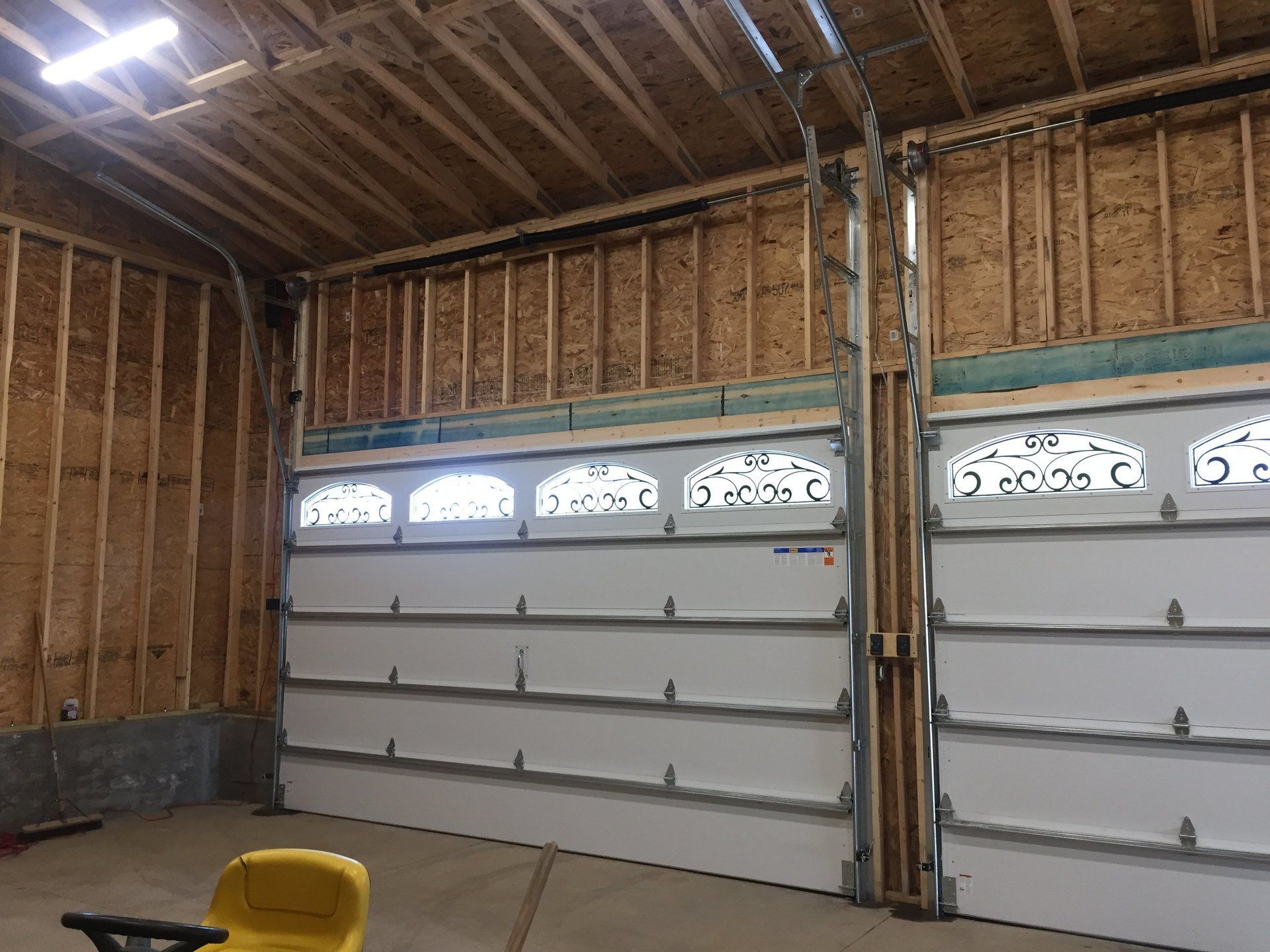 A garage with two garage doors and a yellow toy tractor in it.