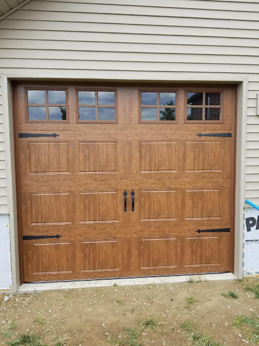 A wooden garage door is sitting in front of a house.