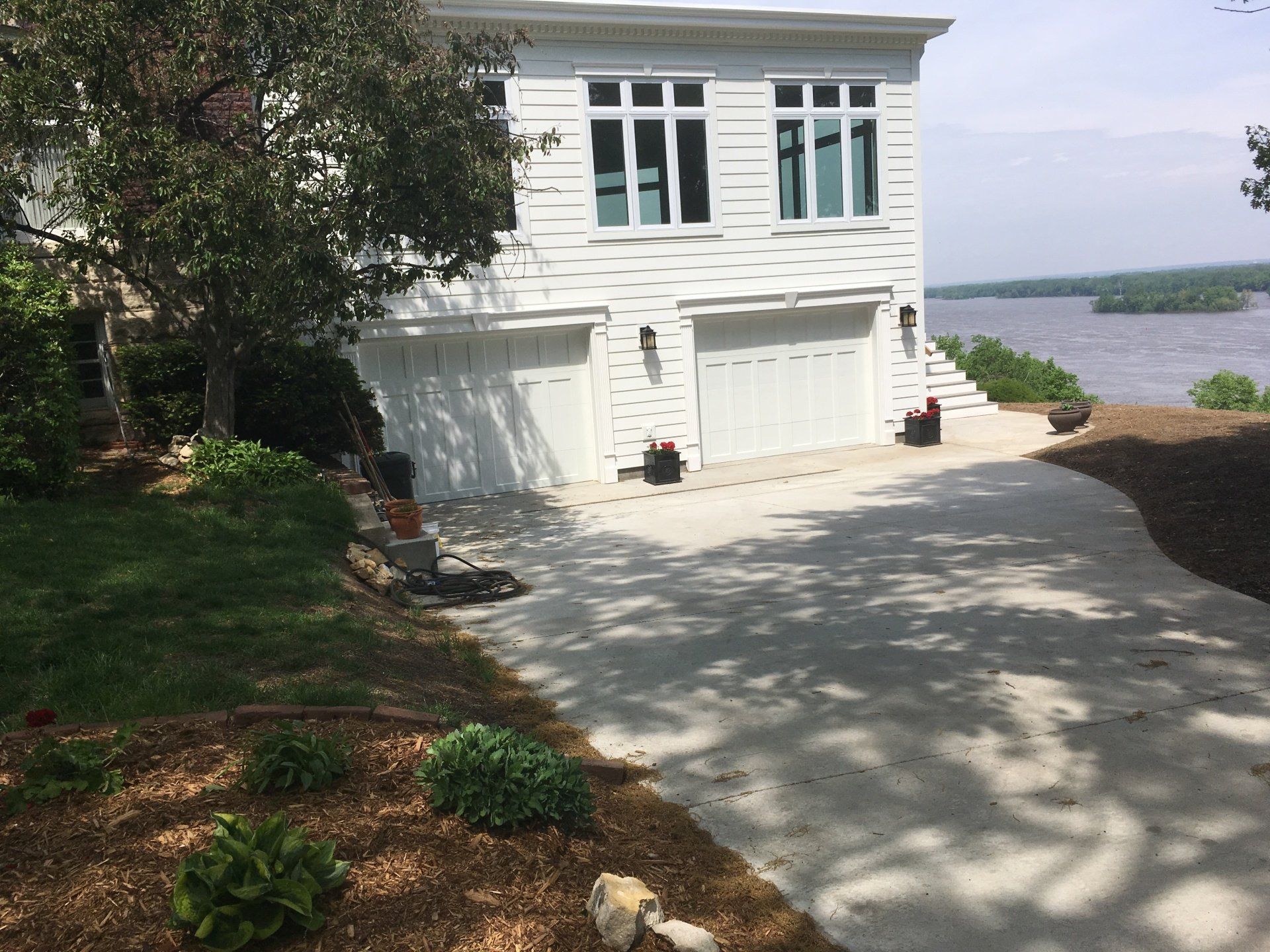 A large white house with a driveway leading to it and a lake in the background.
