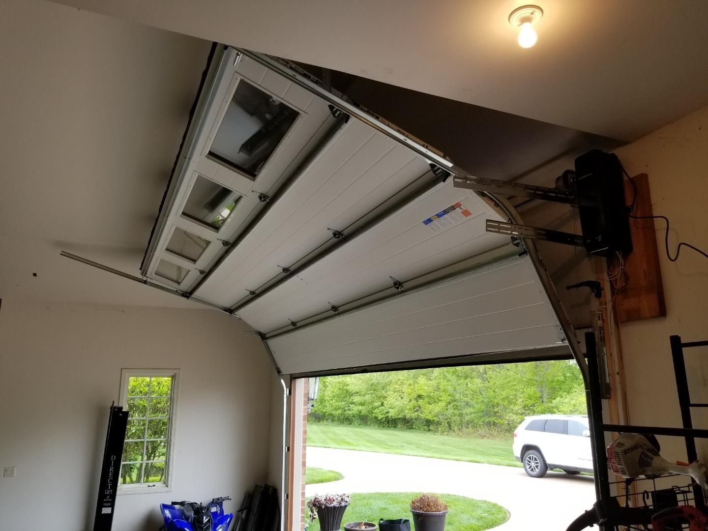 A garage door is open and a car is parked in the driveway.