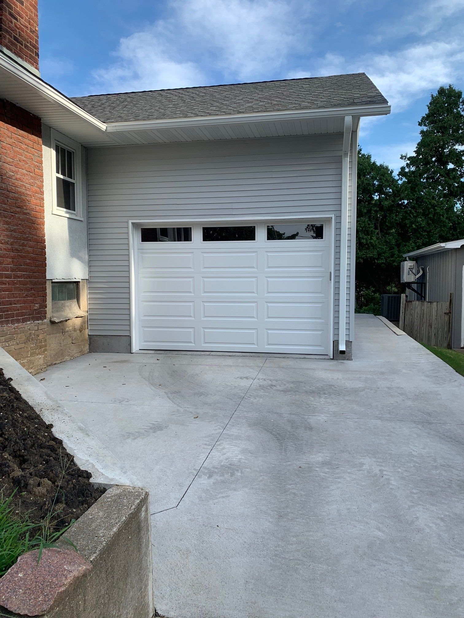 A white garage door is open in front of a brick house.