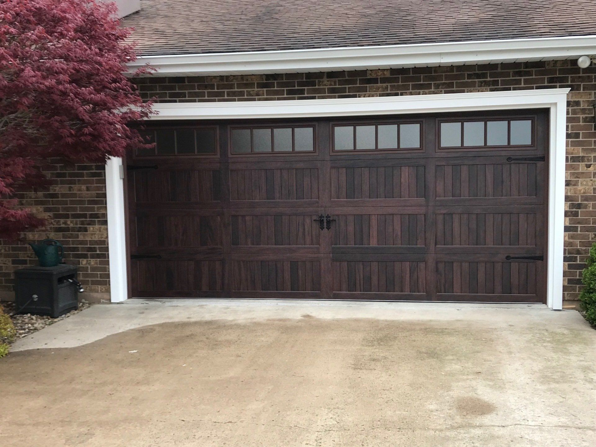 A brown garage door is sitting in front of a brick house.