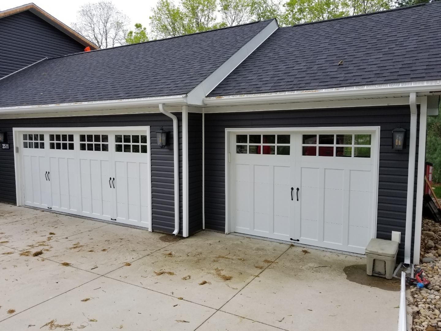 There are two garage doors on the side of a house.