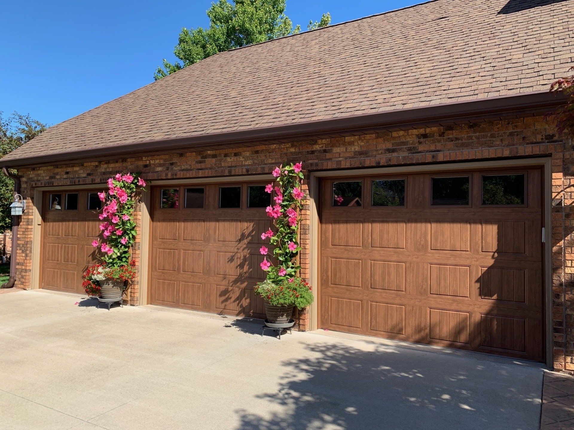 A row of brown garage doors with pink flowers in front of them.