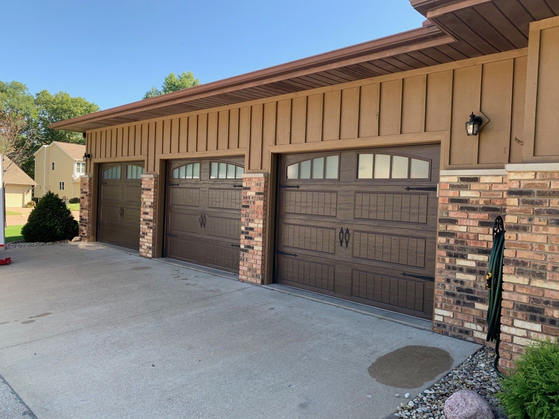 A house with three garage doors and a brick wall