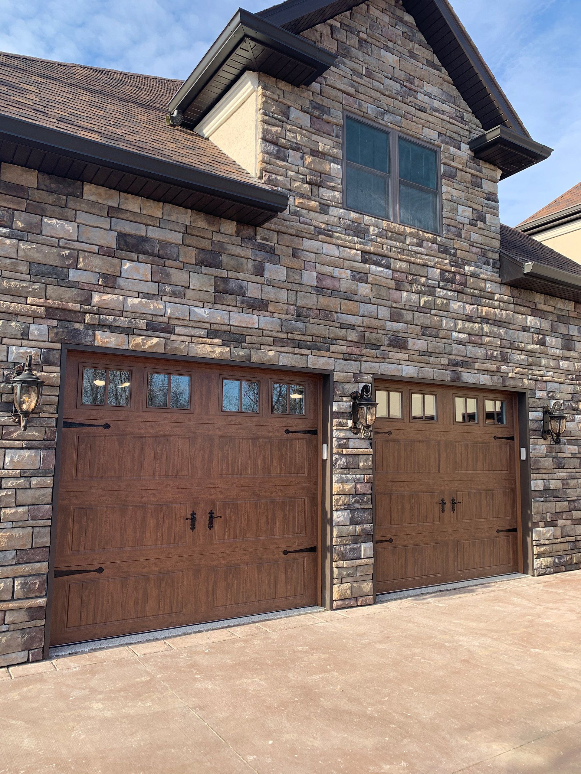 There are two garage doors on the side of a brick building.