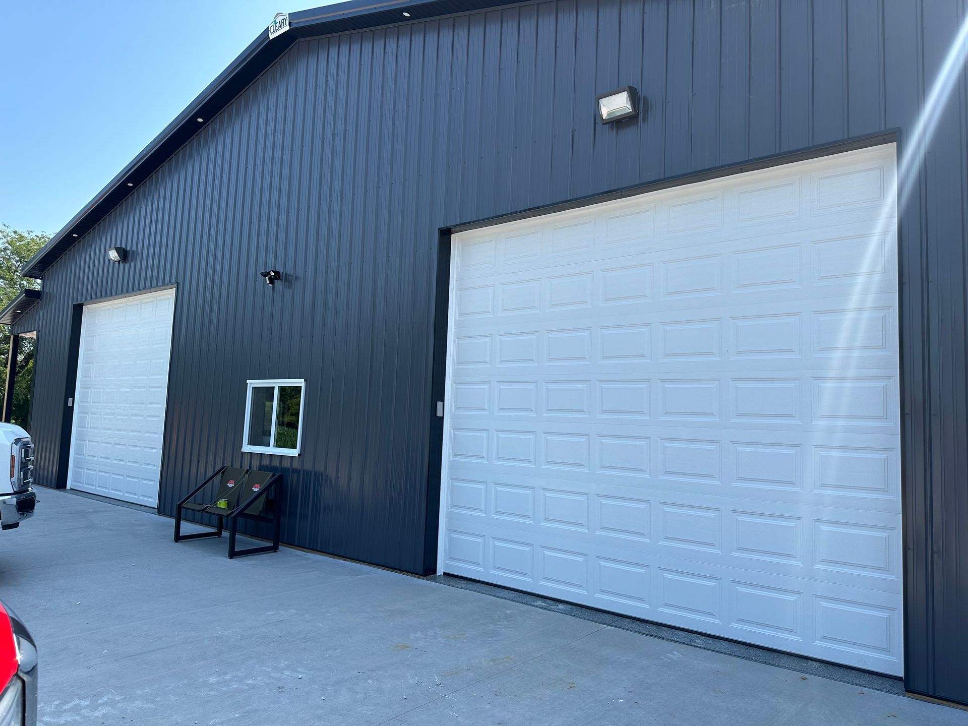 A black building with white garage doors and a truck parked in front of it.