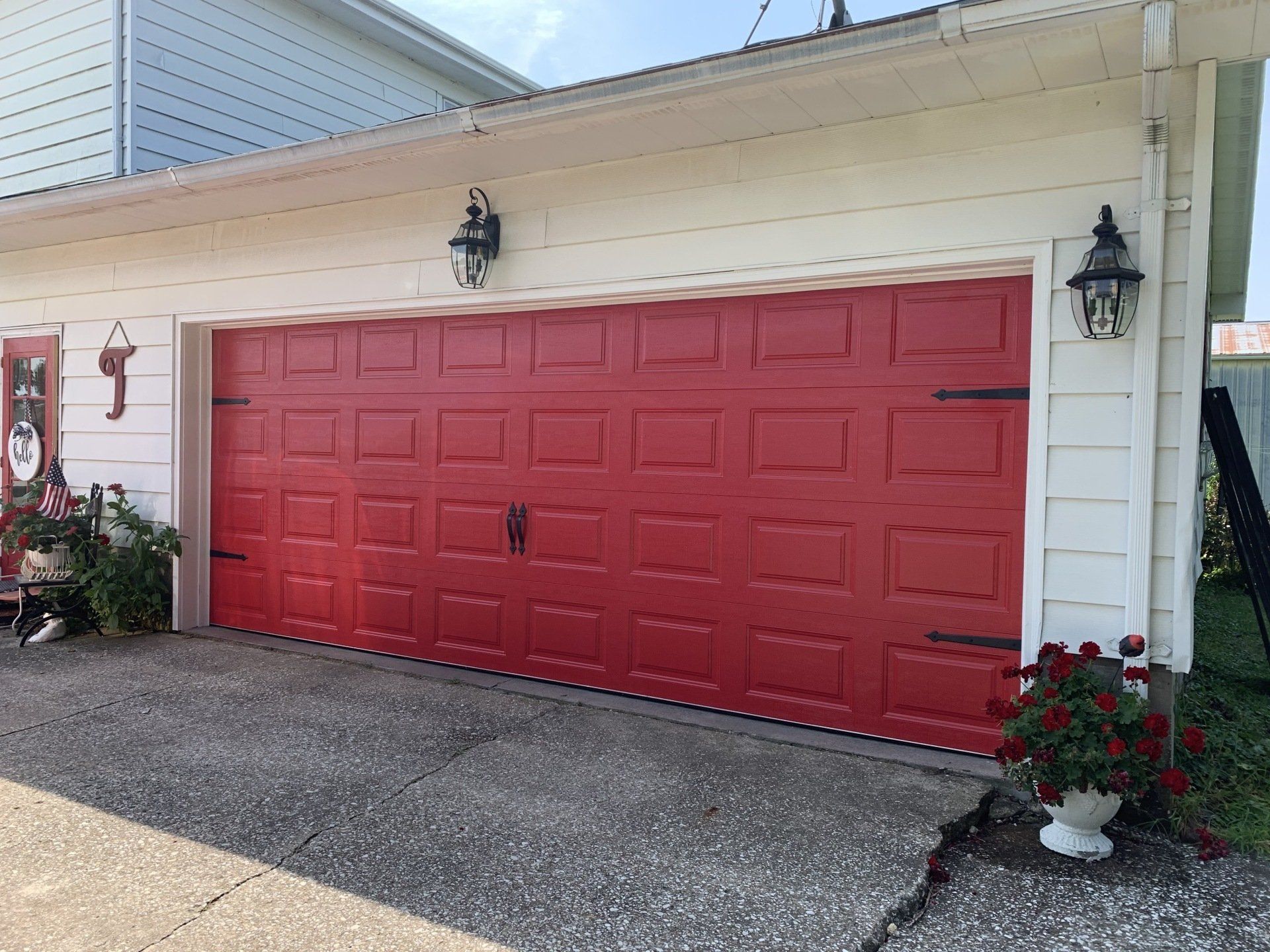 A red garage door is on a white house.