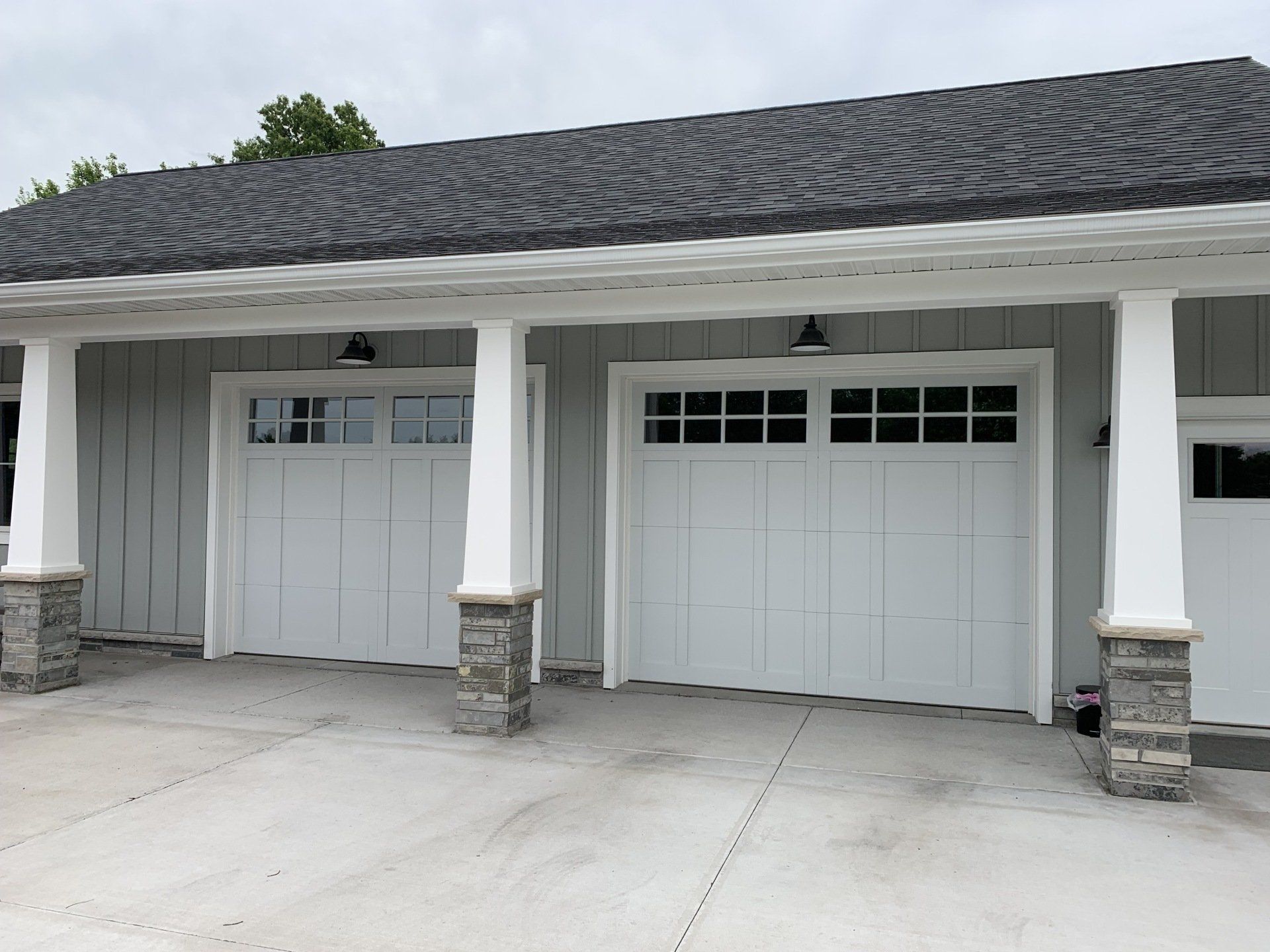 A garage with three white garage doors and a black roof.