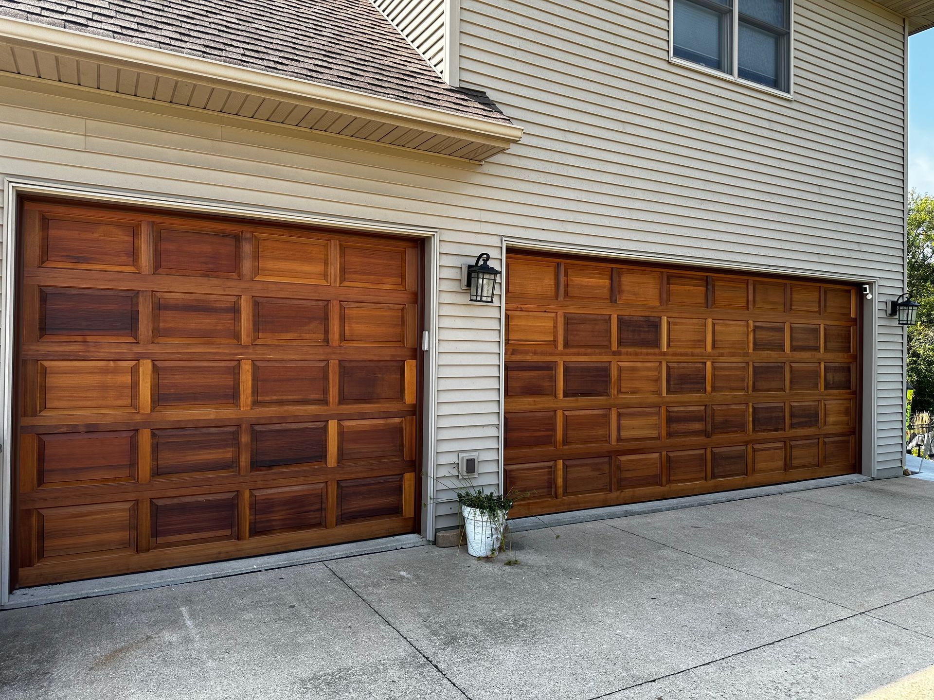 Two wooden garage doors are on the side of a house.