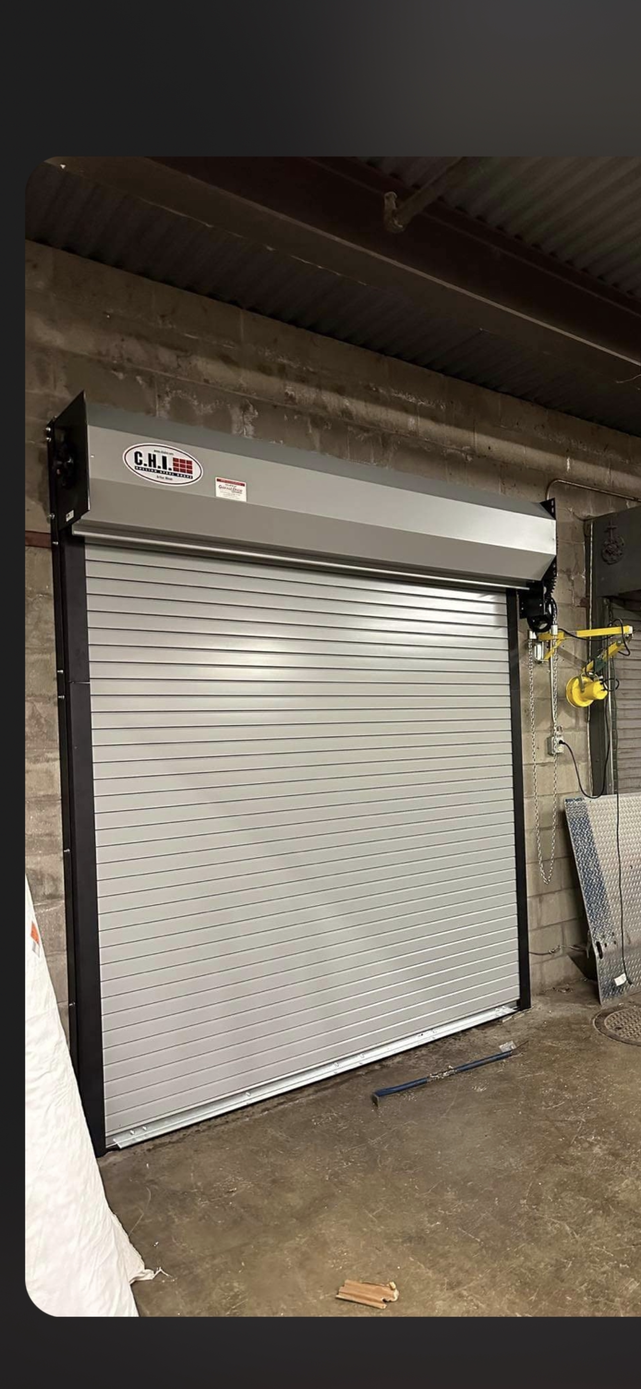 A white garage door is open in a warehouse.