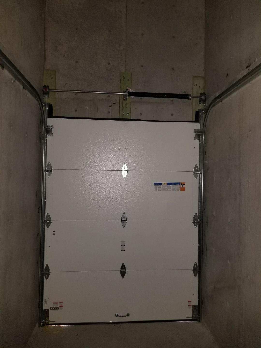 A white garage door is open in a dark room.