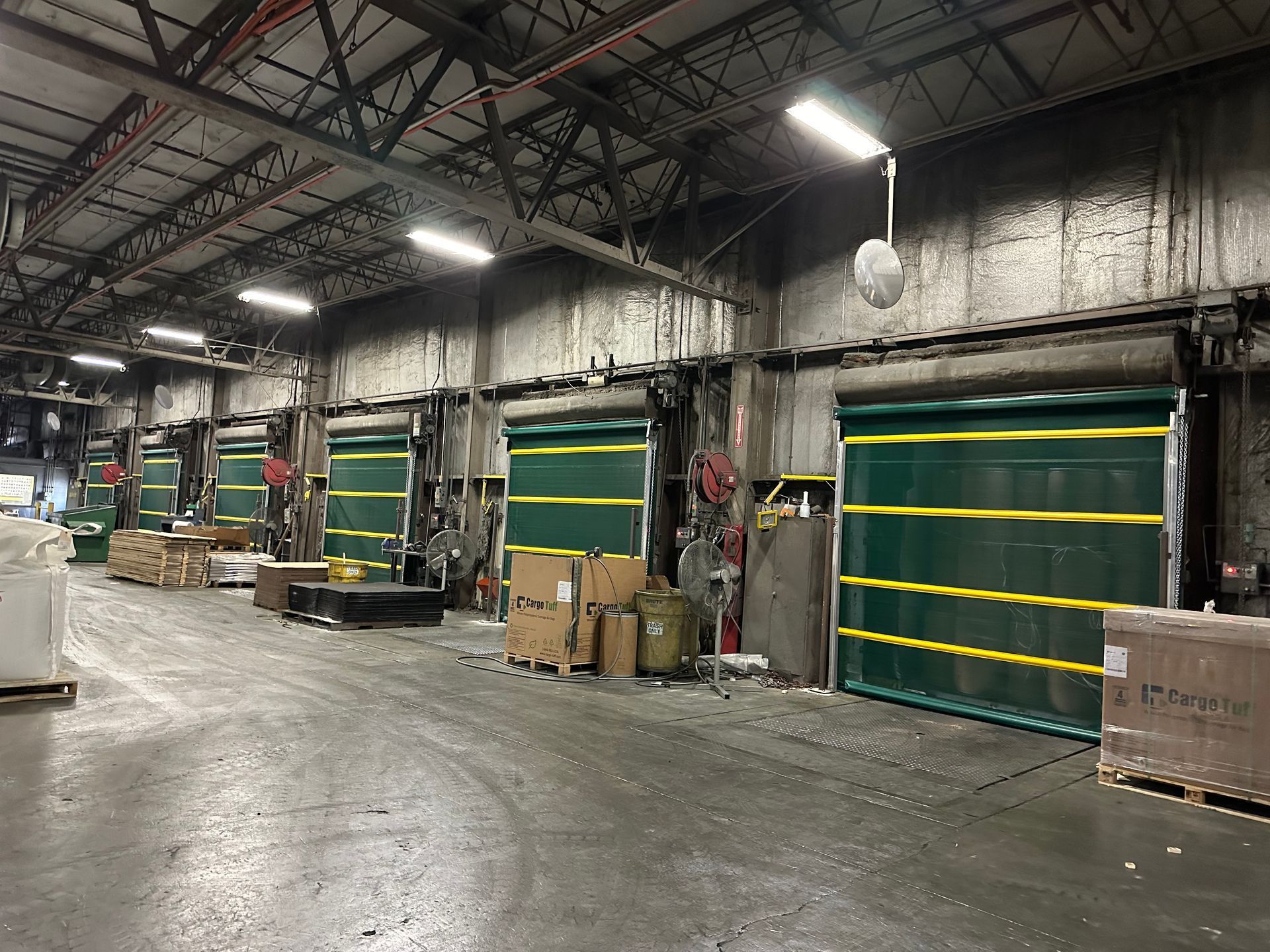 A warehouse filled with lots of boxes and green and yellow doors.