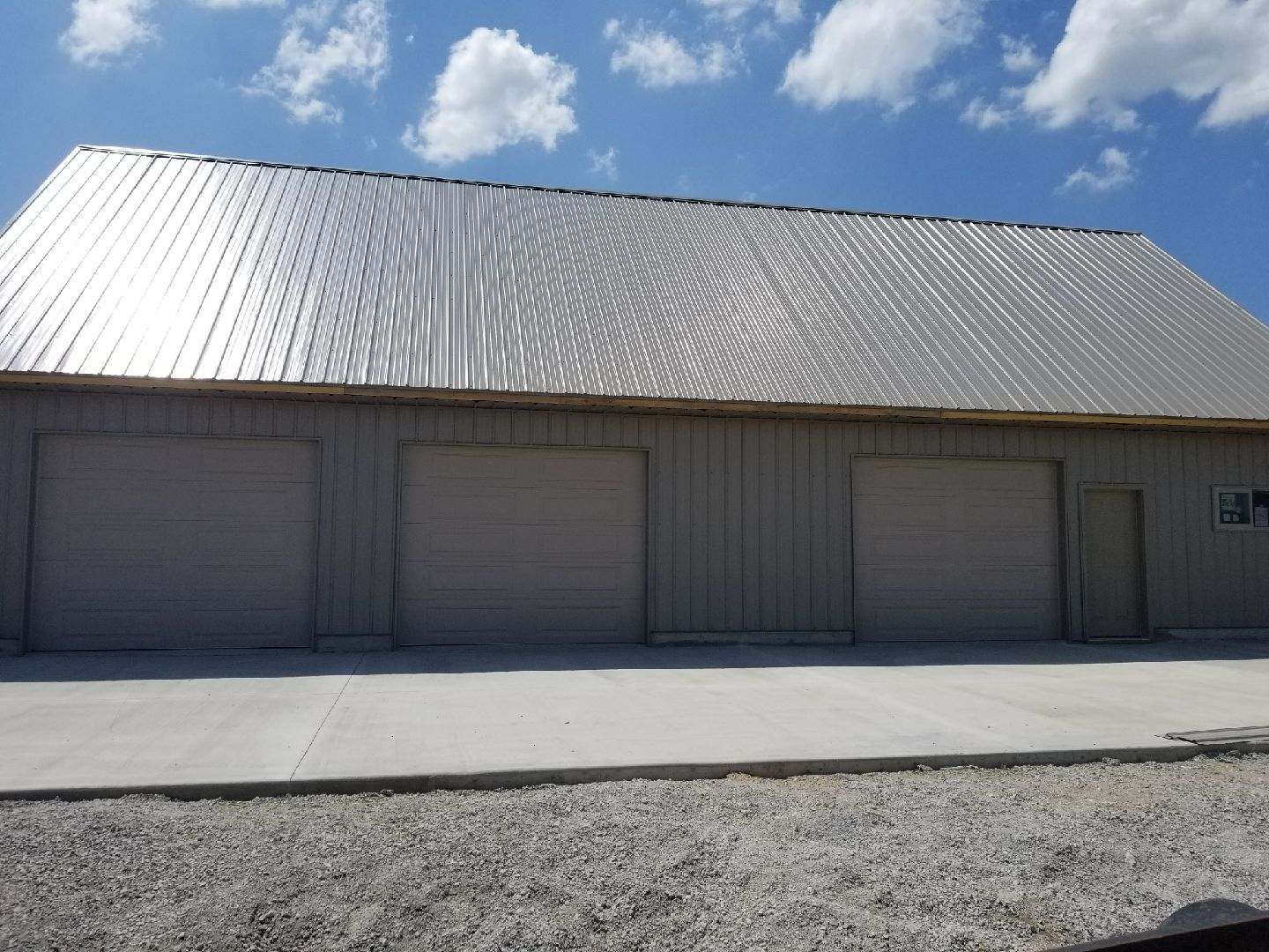 A large building with three garage doors and a metal roof.