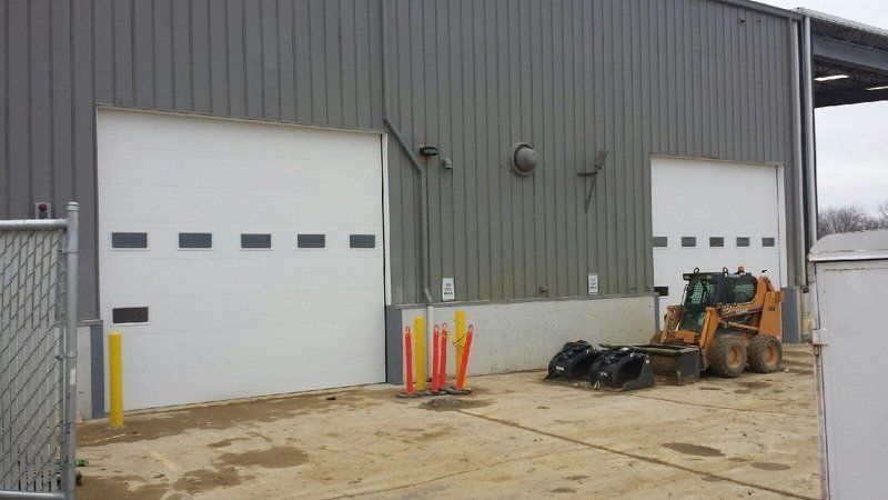 A bulldozer is parked in front of a large garage door.