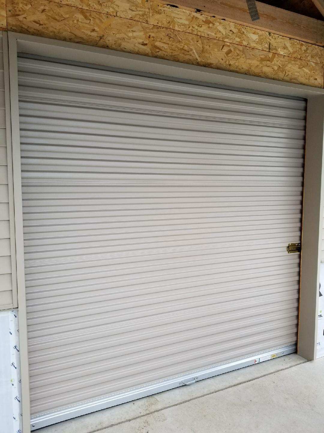 A white garage door is sitting on the side of a building.