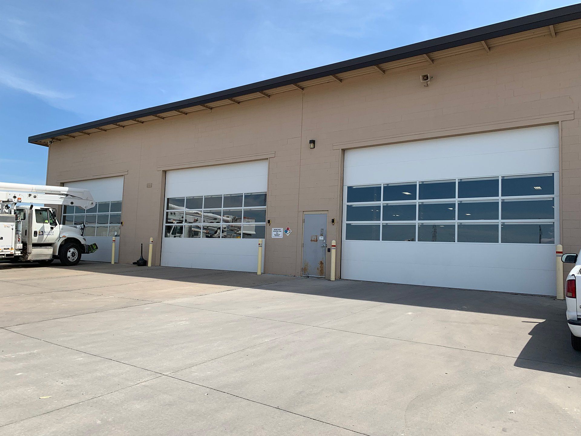 A white truck is parked in front of a building with white garage doors.