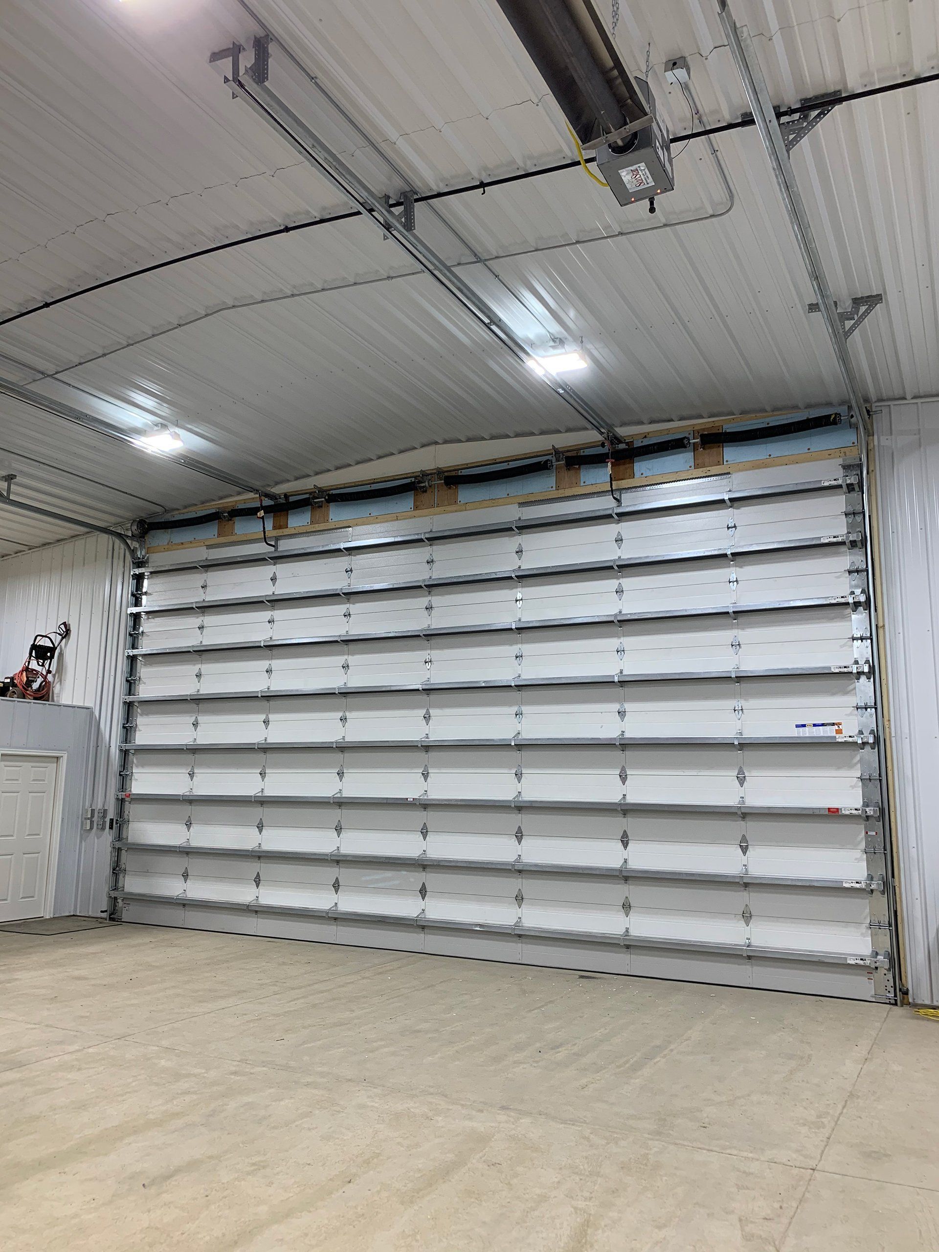 A large white garage door is open in a garage.