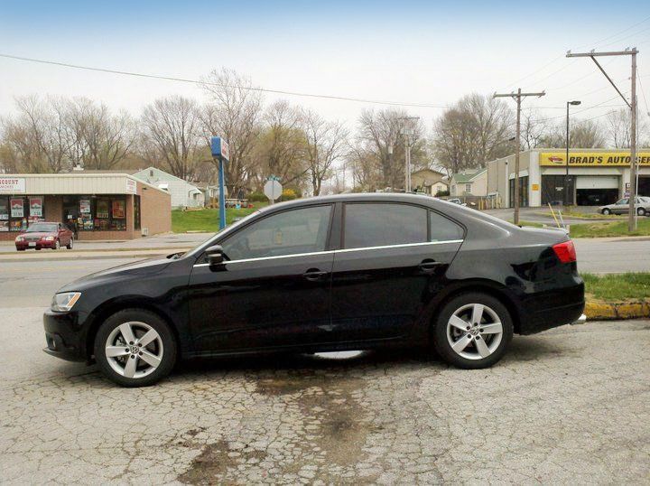 Black sedan parked on a street in front of storefronts and utility poles