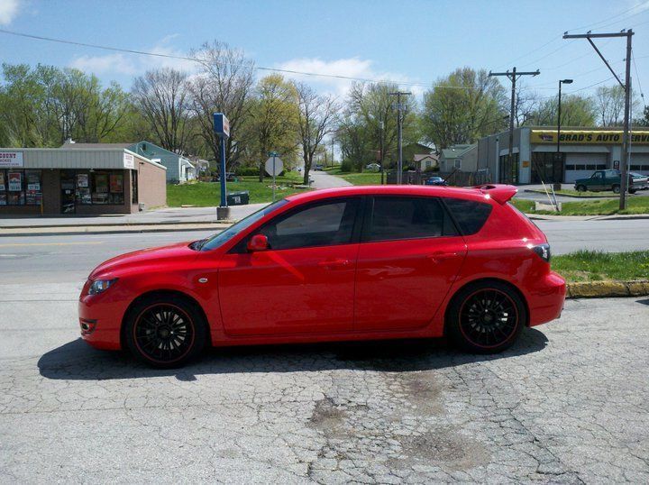 Red hatchback parked beside a street on a sunny day